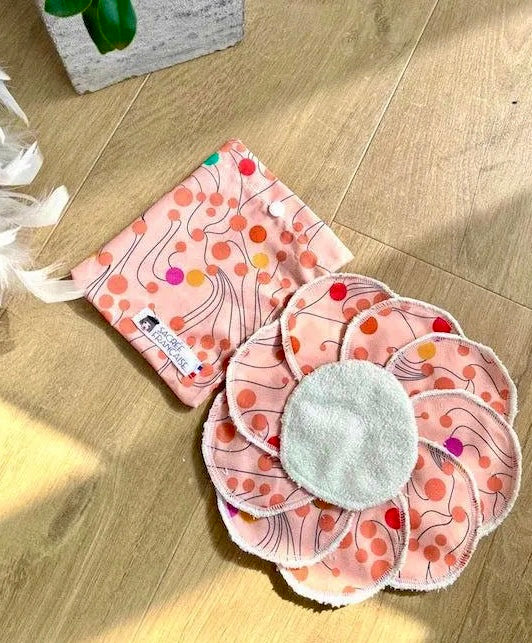 Reusable pink floral patterned makeup remover pads with matching pouch on wood floor